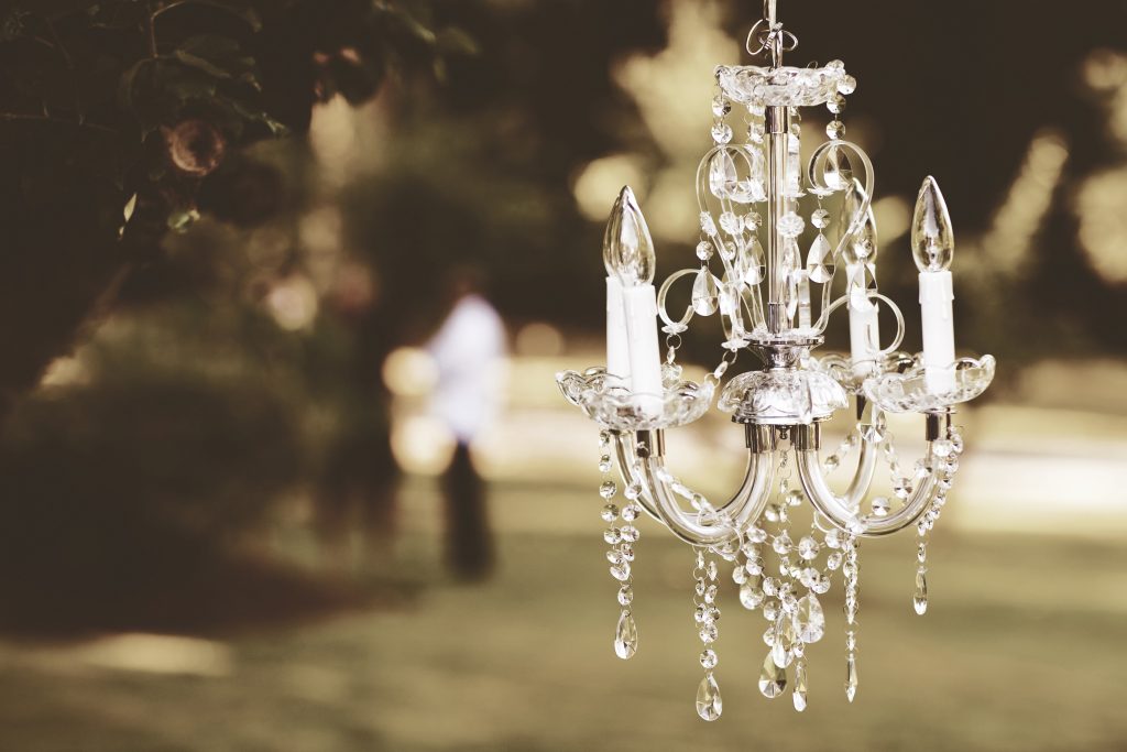 Kryształowy żyrandol powieszony na gałęzi podczas wesela plenerowego w ogrodzie